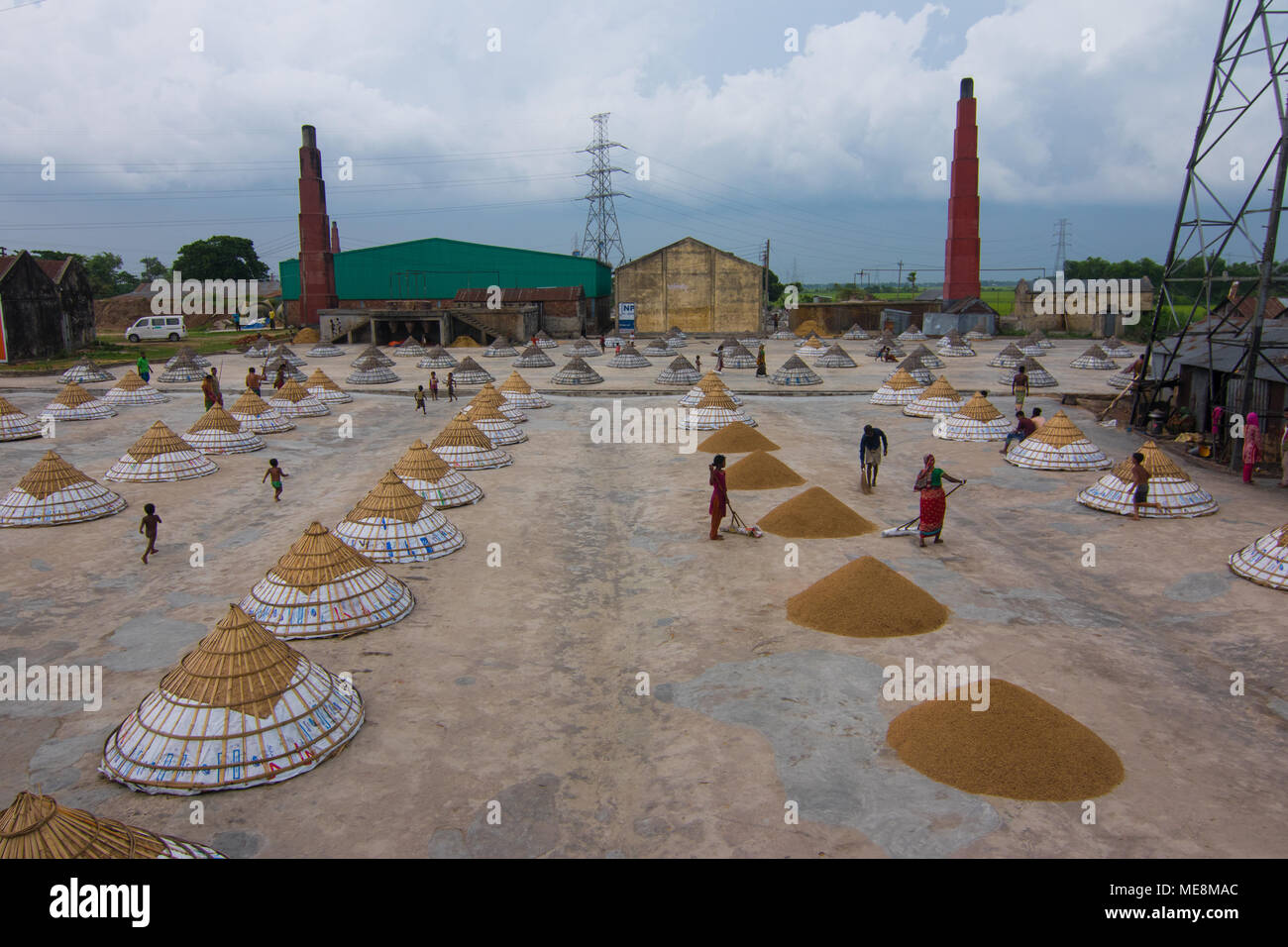 Workers in a rice mill shelter their product with pyramid-shaped covers ...