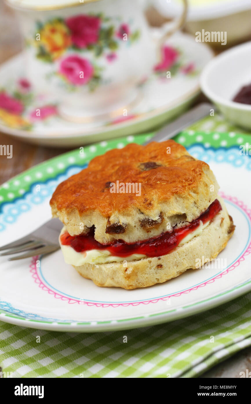Delicious traditional English scone with fresh clotted cream and strawberry jam, closeup Stock Photo
