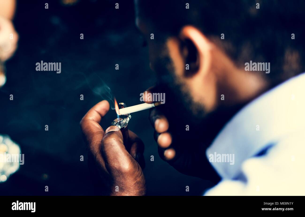 Rear view of man lighting up the cigarette in his mouth Stock Photo