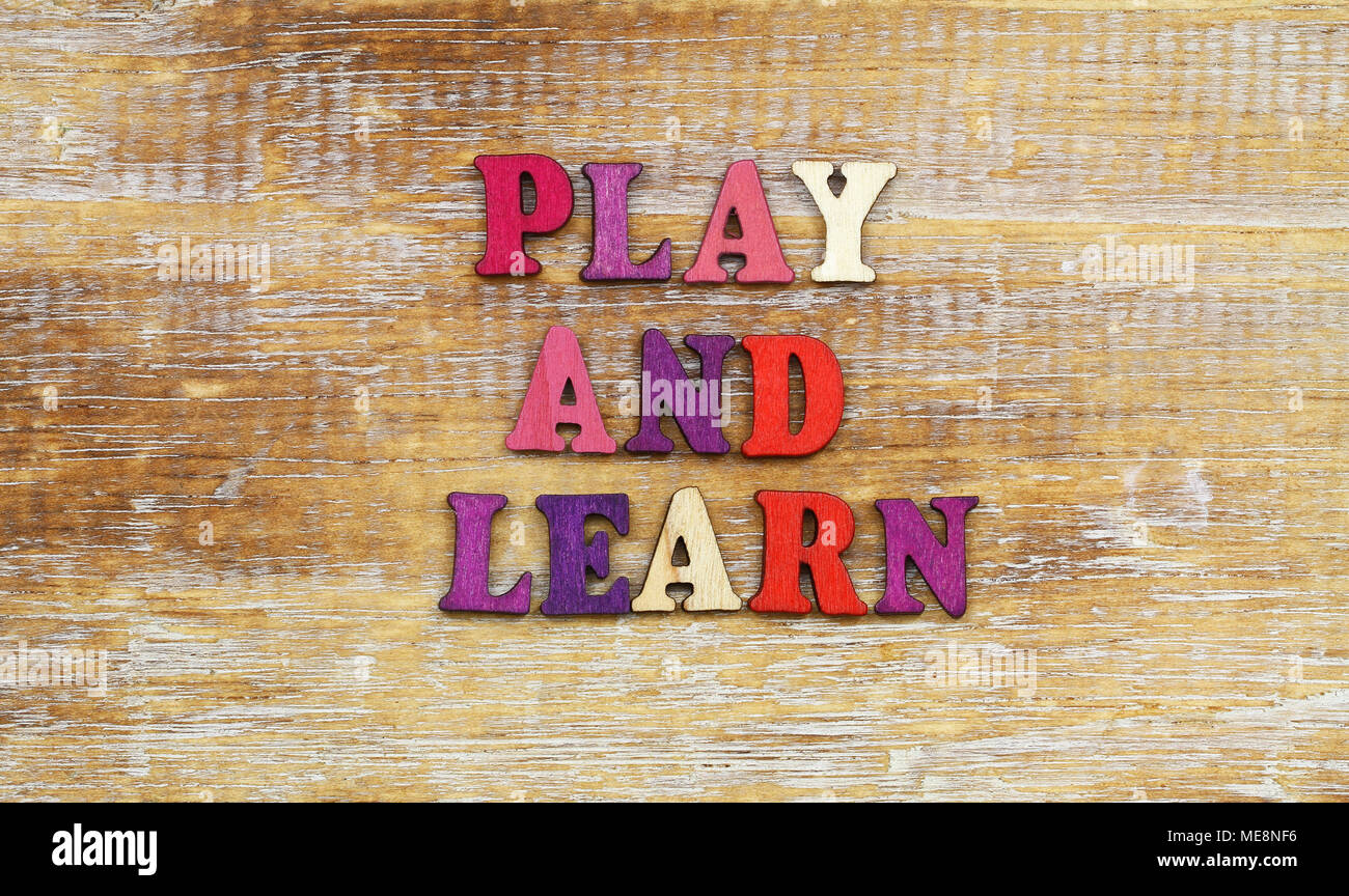 Play and learn sign written with colorful wooden letters on rustic surface Stock Photo
