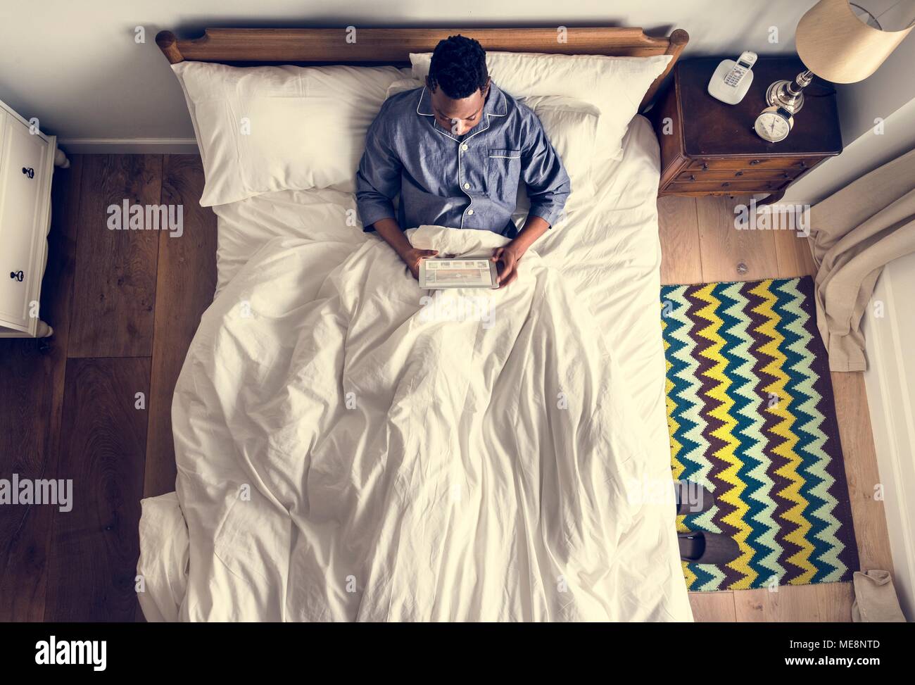 Man in bed using a digital device Stock Photo