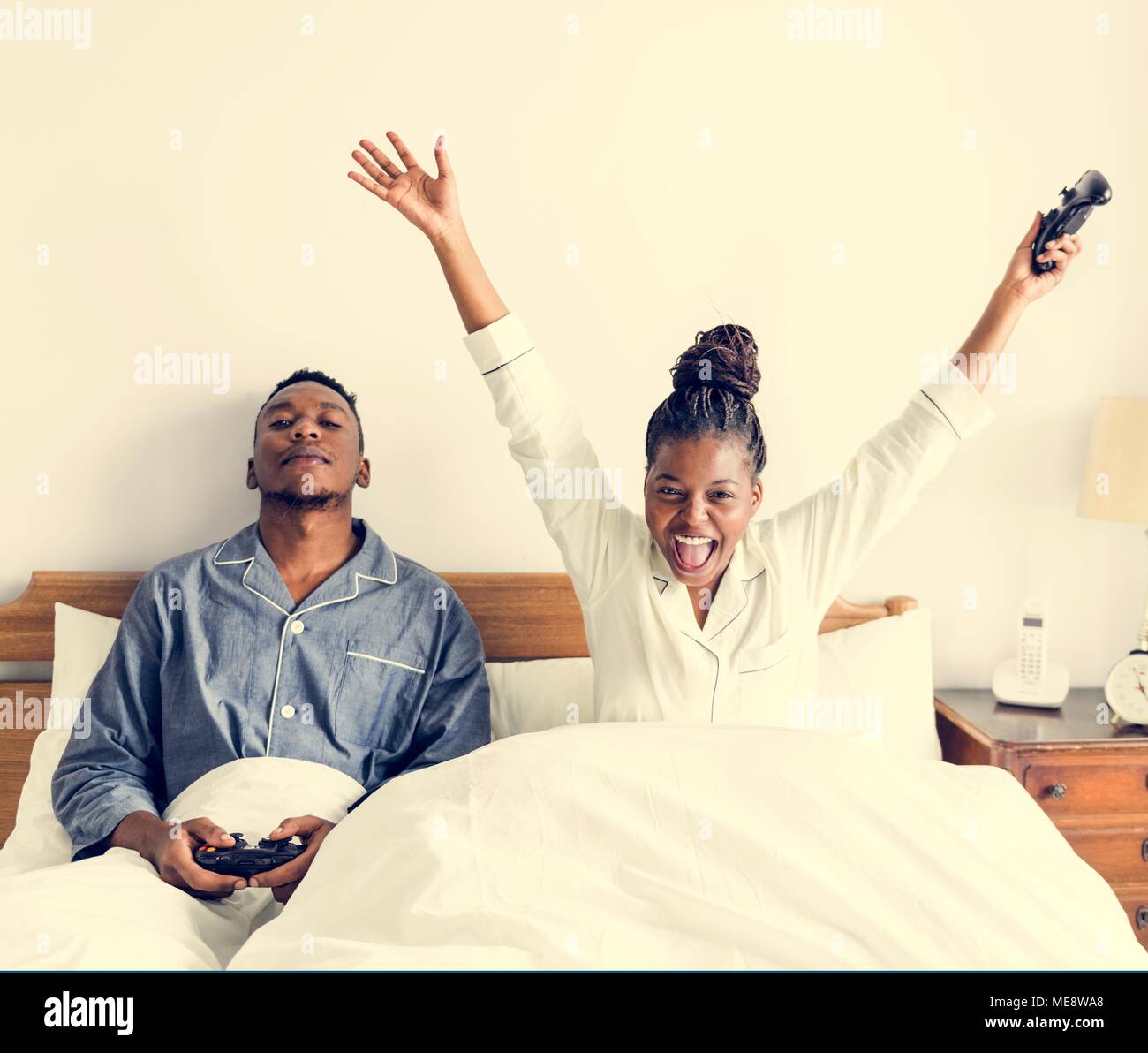 A happy couple playing video game in bed Stock Photo