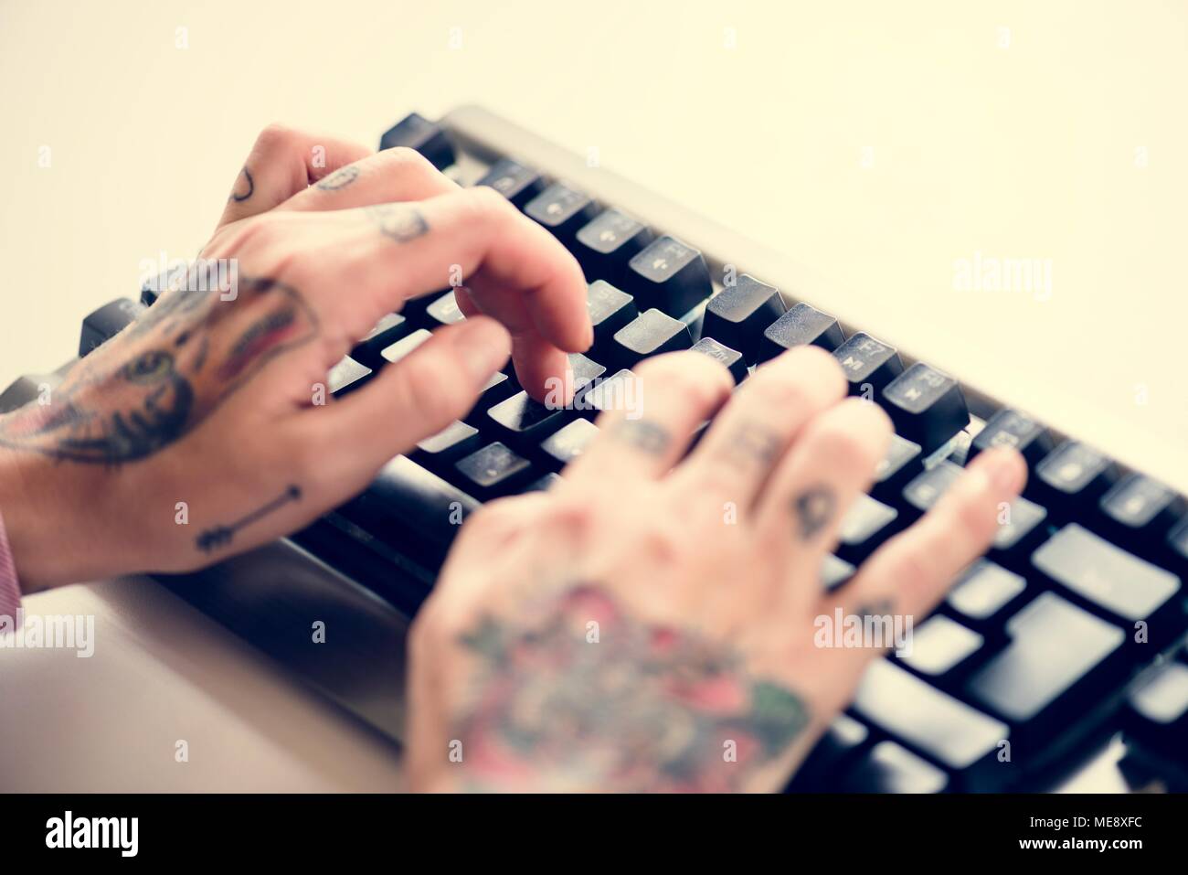Hands with tattoo typing on a keyboard Stock Photo
