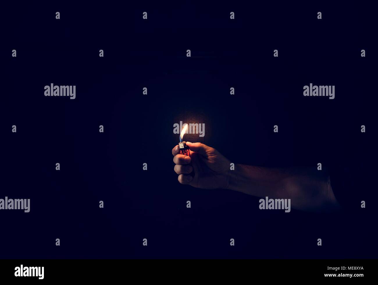 Hand holding lighter in the dark Stock Photo