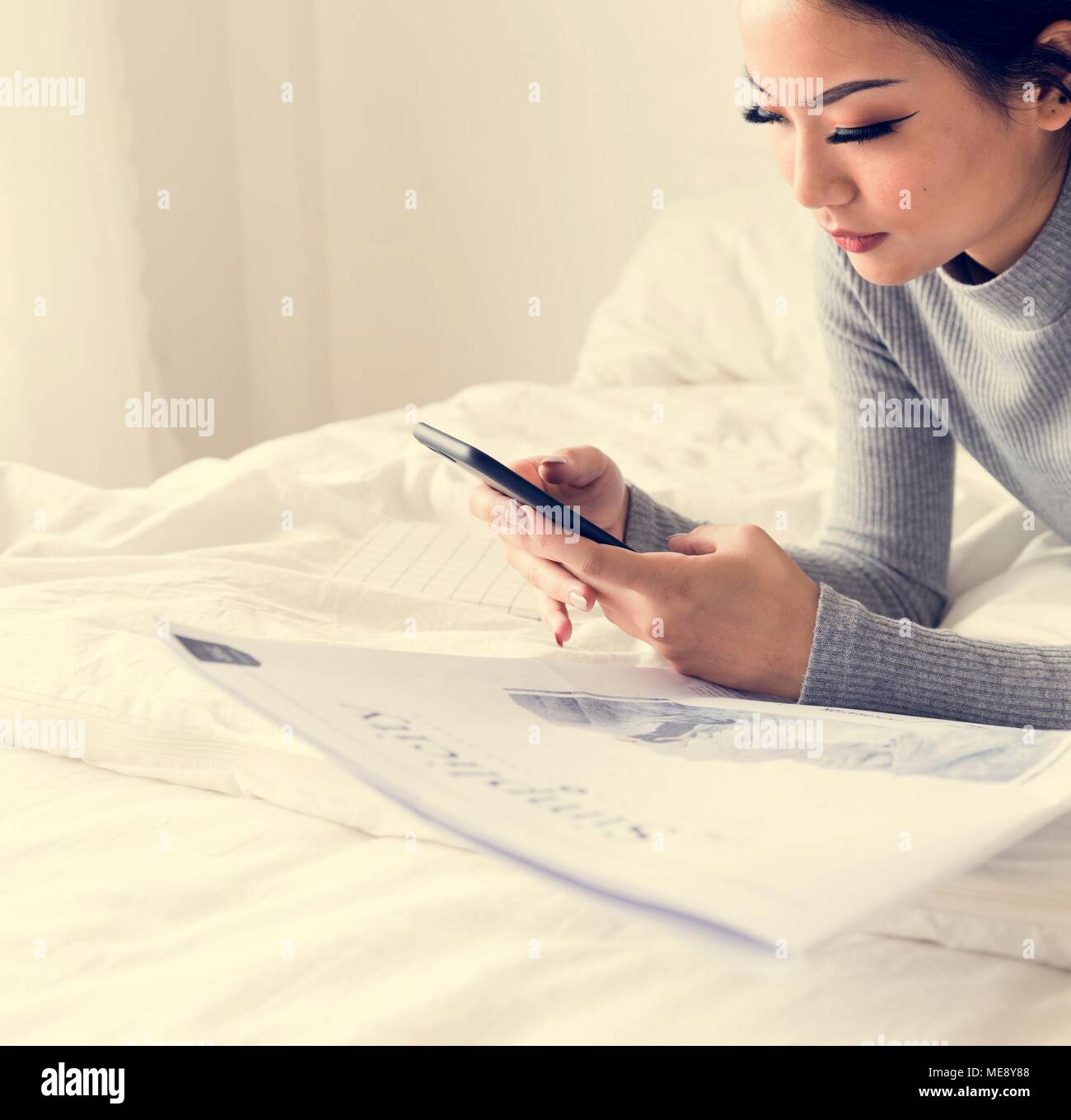 Asian woman lying on bed using mobile phone Stock Photo - Alamy