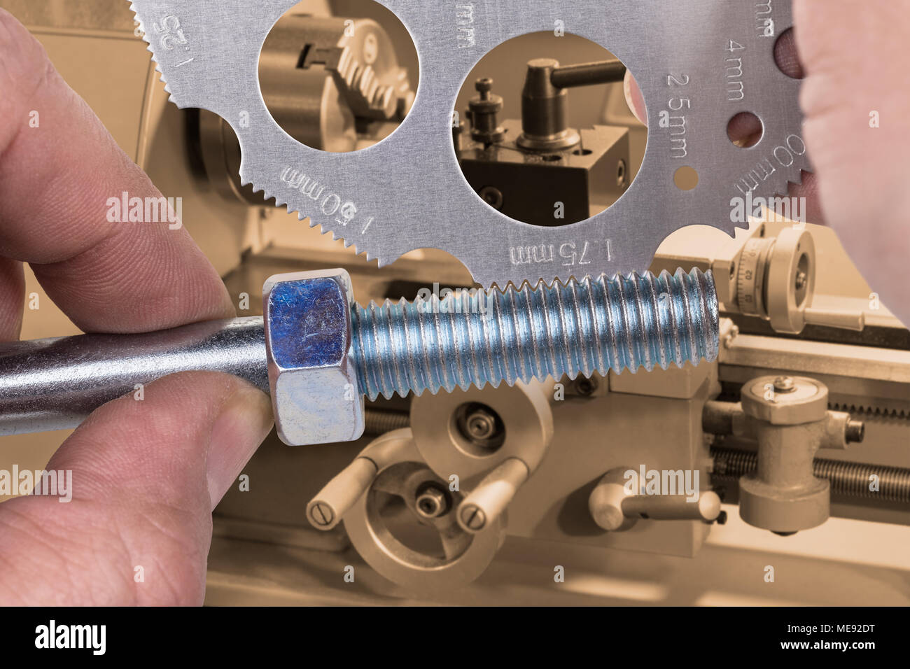 Measuring by screw pitch gauge with lathe in background. Measurement of thread on steel bolt with nut and detail of turner's hands in workplace. Stock Photo
