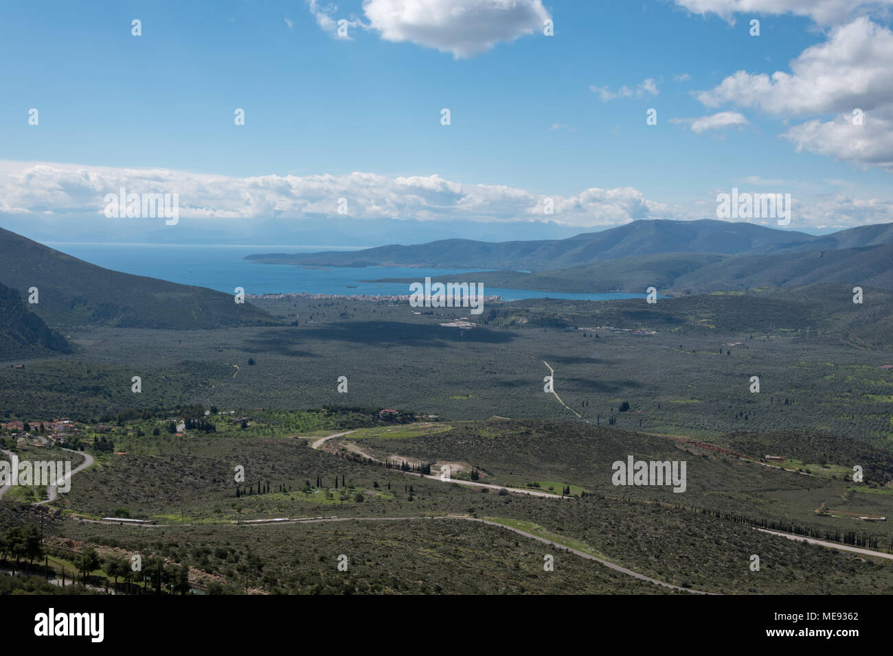 The view of Itea in Greece from Delphi on a sunny day with some clouds in the sky. The Peloponnese is also visible. Stock Photo