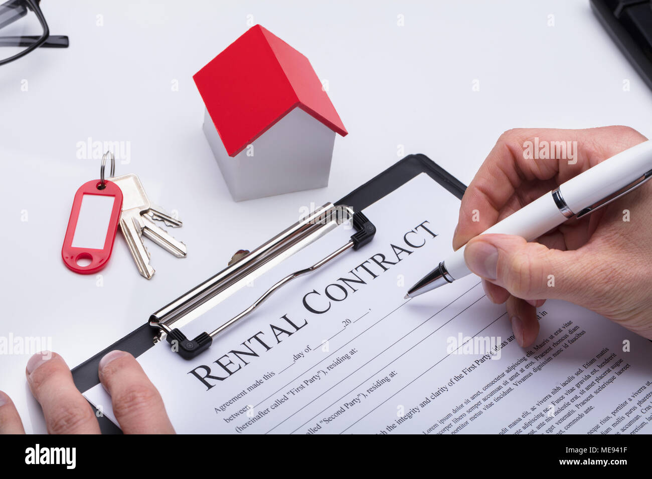 Human Hand Filling Rental Contract Form With House Model And Key On
