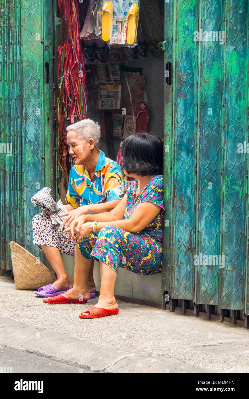 Two women one elderly and the other middle age sitting in the doorway having a quiet conversation in Ho Chi Minh City, Vietnam. Stock Photo