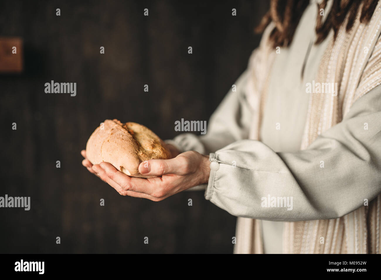 Jesus Christ with bread in hands, sacred food, crucifixion cross on
