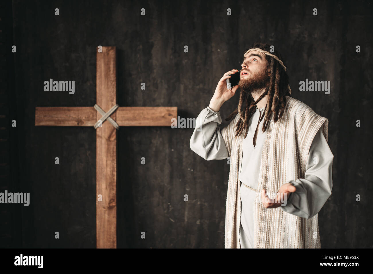 Man in the image of Jesus Christ talking to God by mobile phone,  crucifixion cross on black background Stock Photo - Alamy