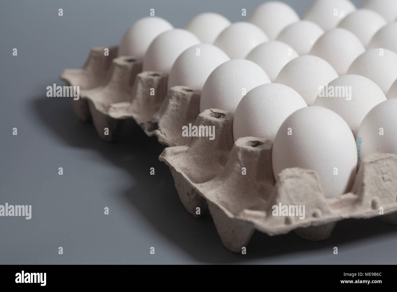 Cardboard egg box with chicken white eggs on gray Stock Photo - Alamy