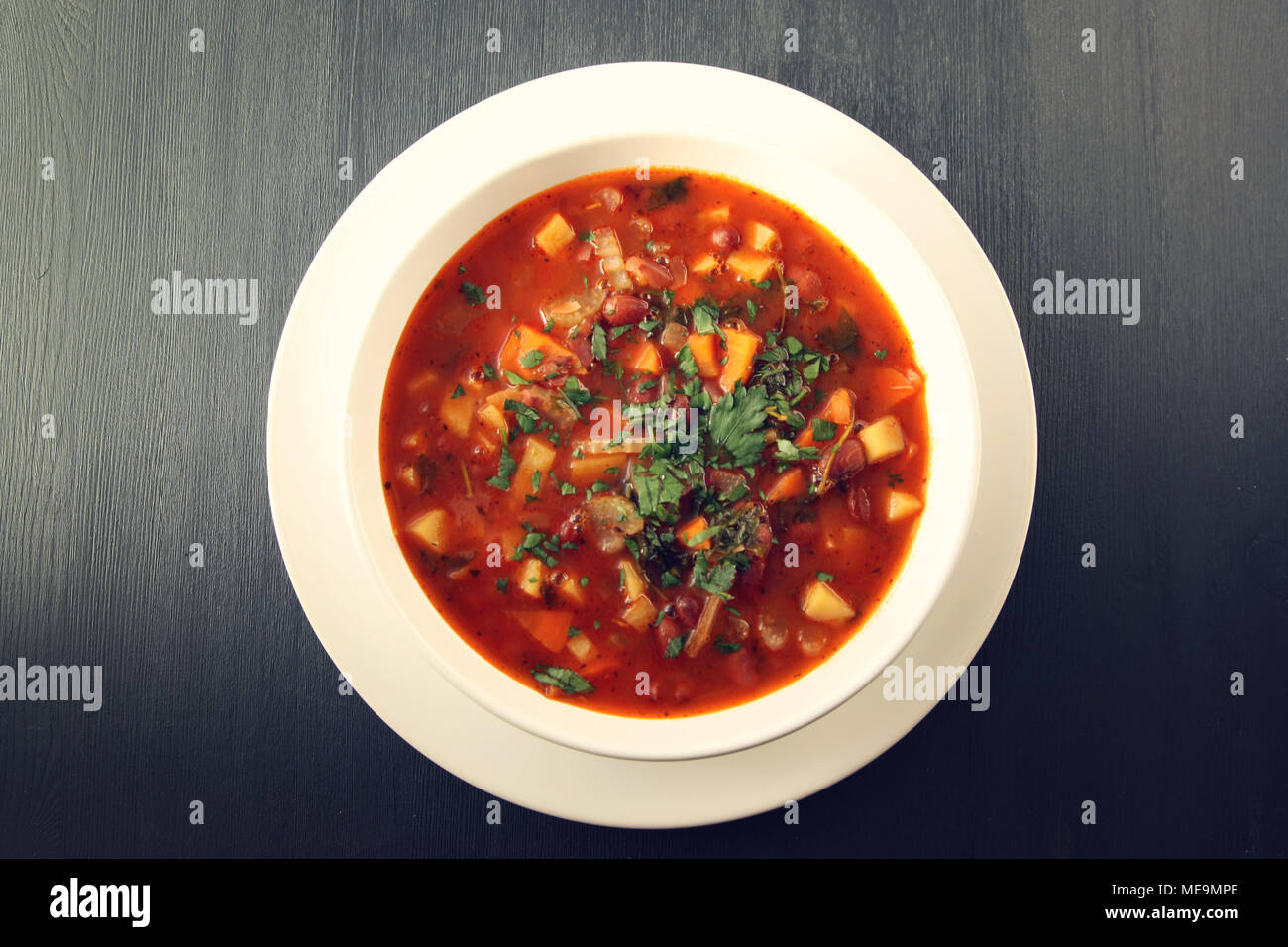 Tomato soup with red beans, potato and carrot. Vegan diet. European cuisine. Vegetarian dish. Main course. Organic meal. Copy space. Top view. Stock Photo