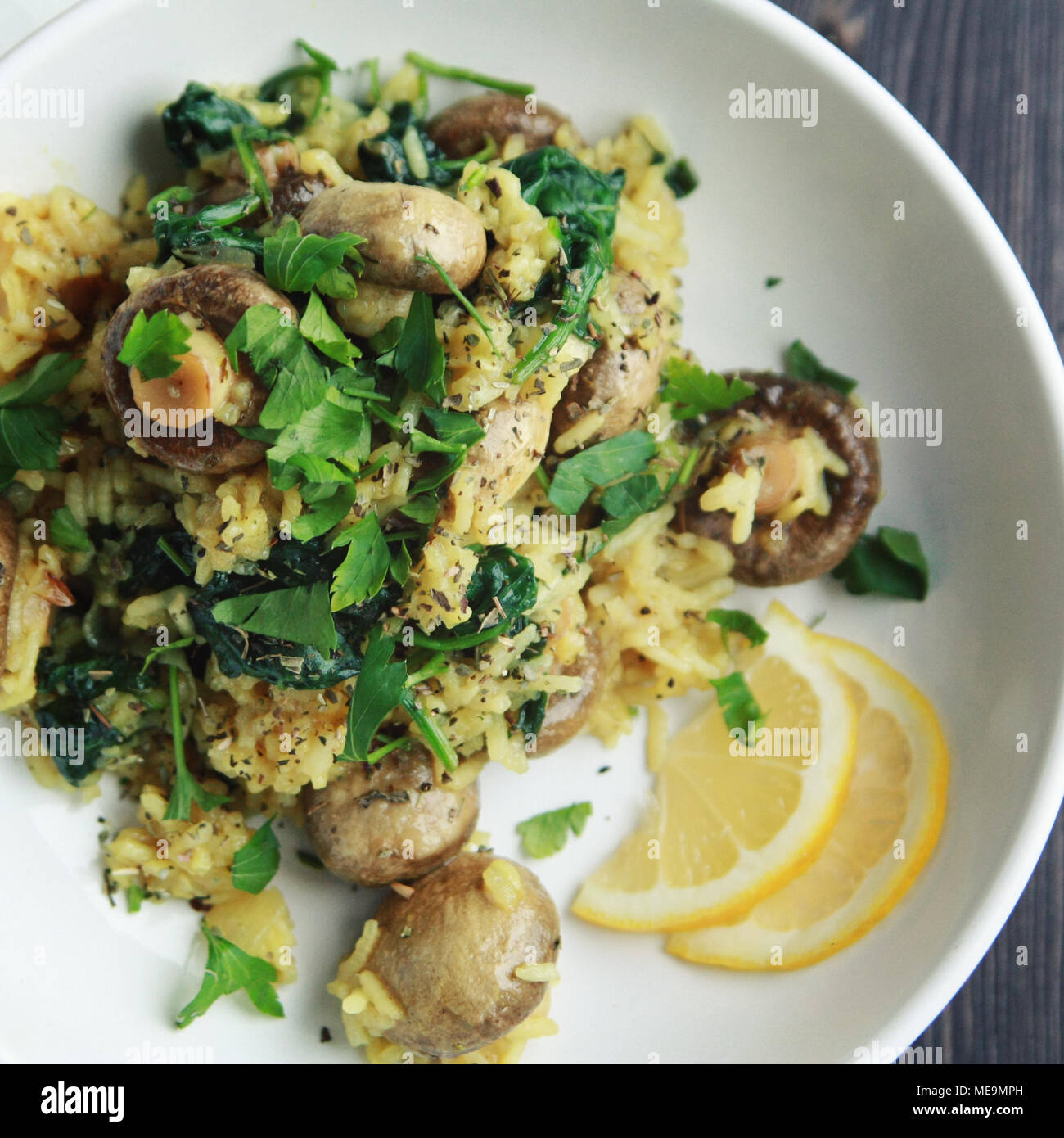 Vegetarian turmeric rice in the white bowl. Vegan dish. European cuisine. Yellow rice with mushrooms and spinach. Meatless. Toned photo. Top view. Stock Photo