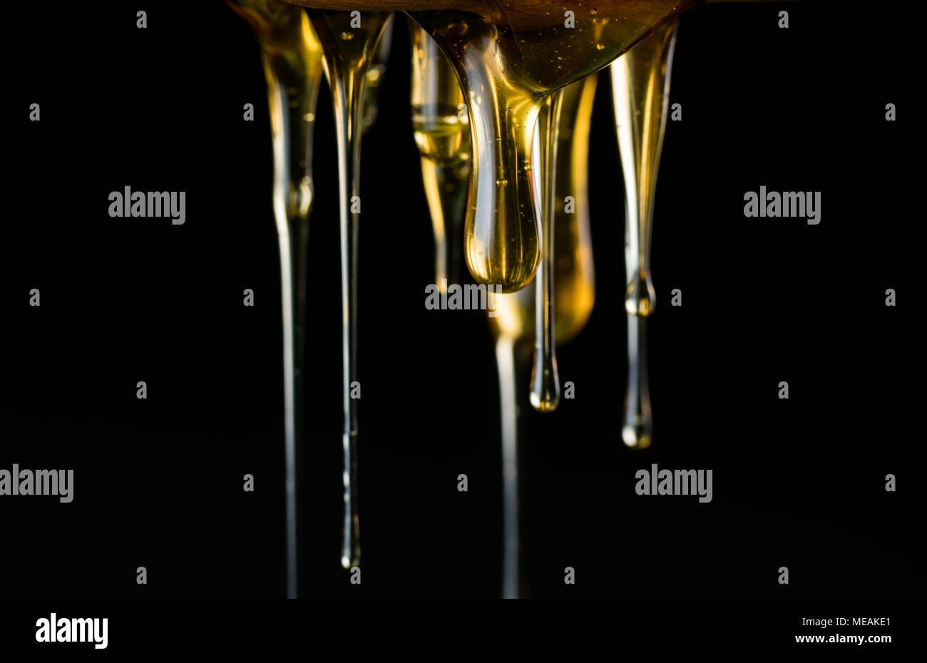Multiple Strings of Honey Drip in front of dark background Stock Photo Alamy
