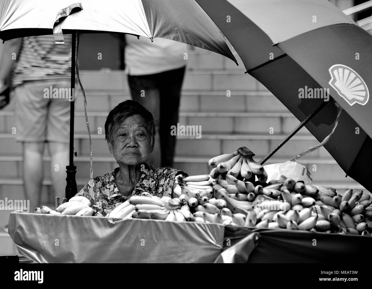 Singapore - April 13th 2018: Elderly Chinese lady selling bananas at her roadside stall in Chinatown, Singapore Stock Photo