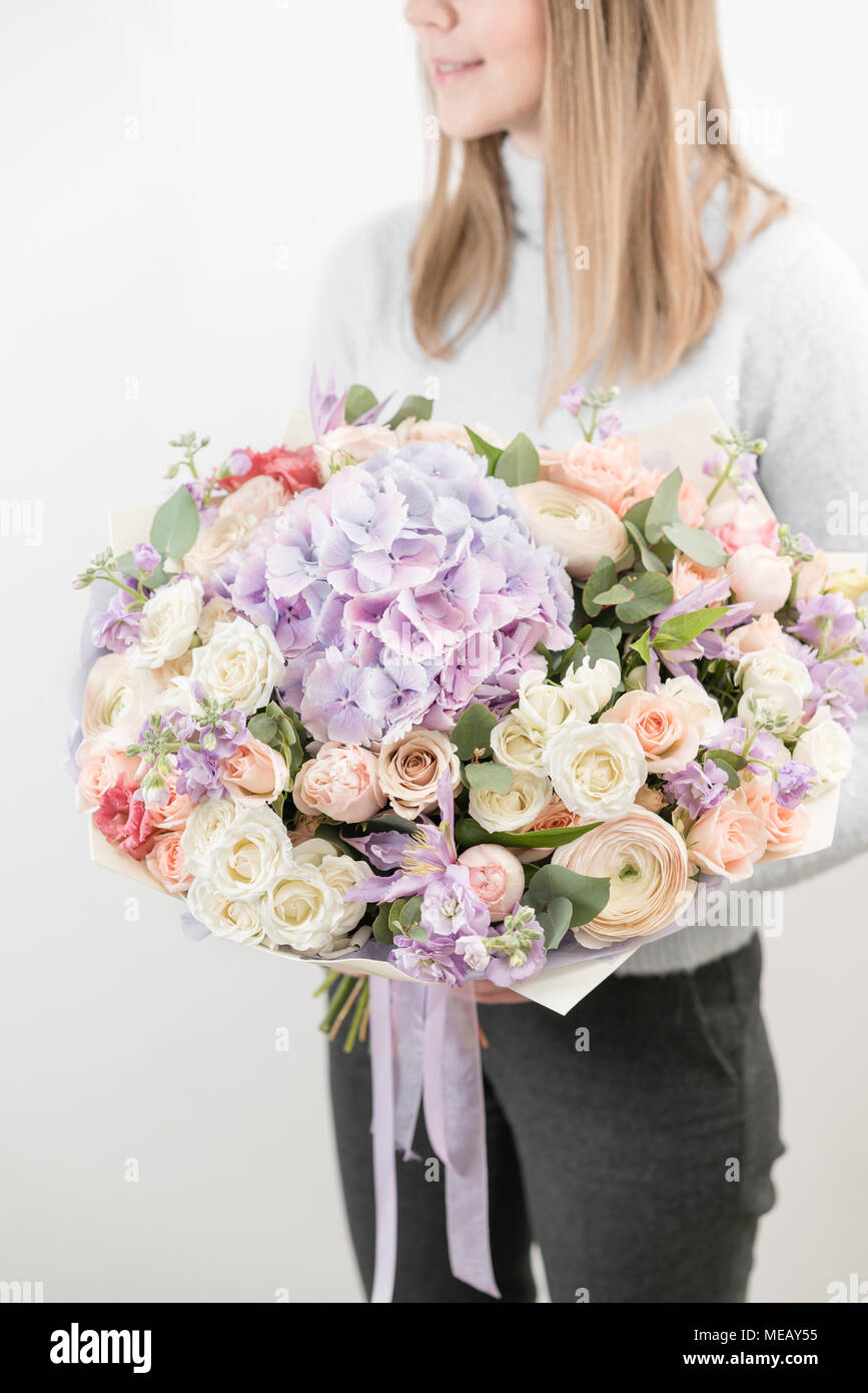 lilac and light bouquet of beautiful flowers in women's hands. Floristry concept. Spring colors. the work of the florist at a flower shop. Vertical photo Stock Photo