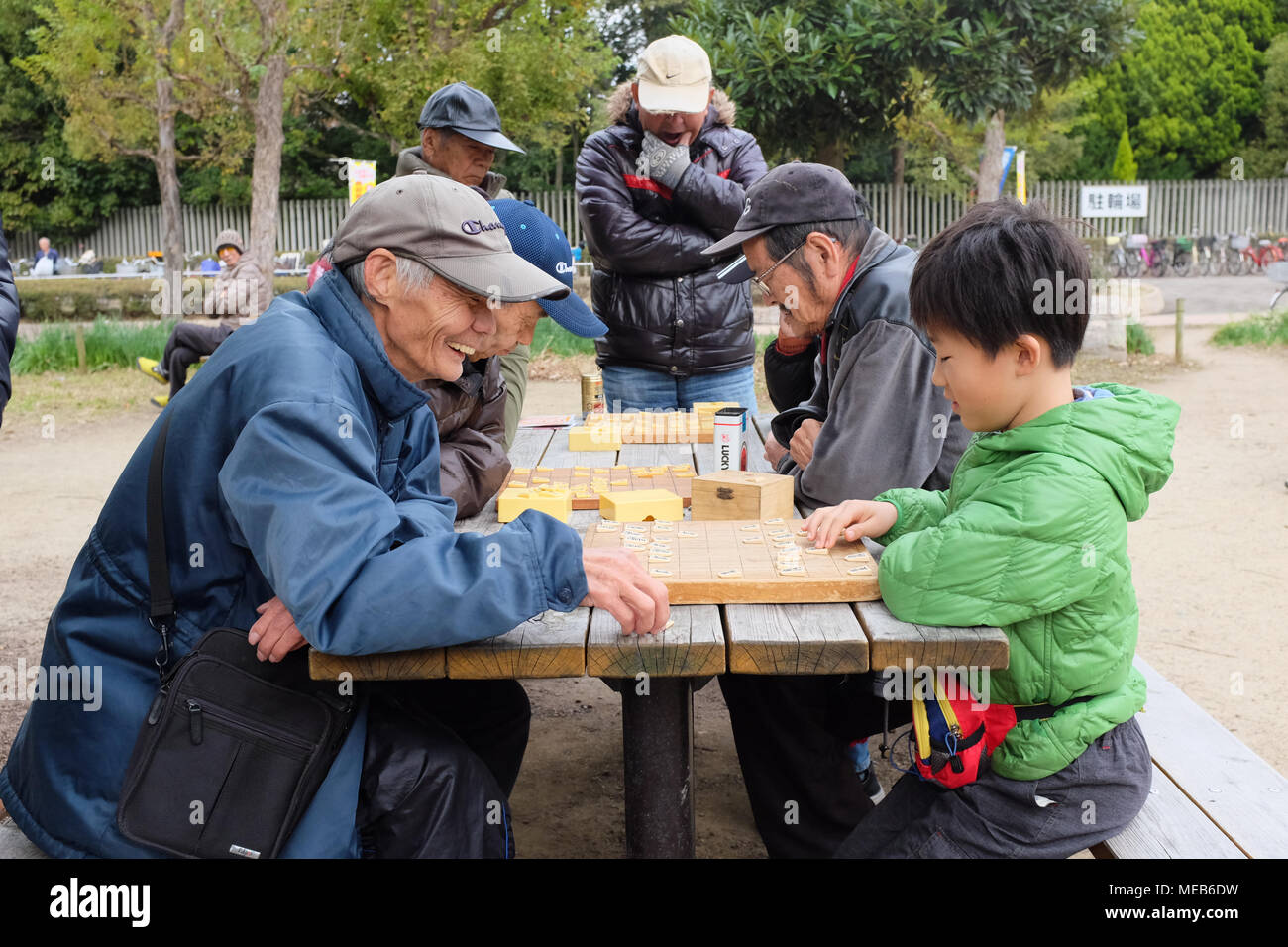 An elderly Japanese man playing chess-style game of shogi with a young boy in a park in Osaka, Japan. Stock Photo