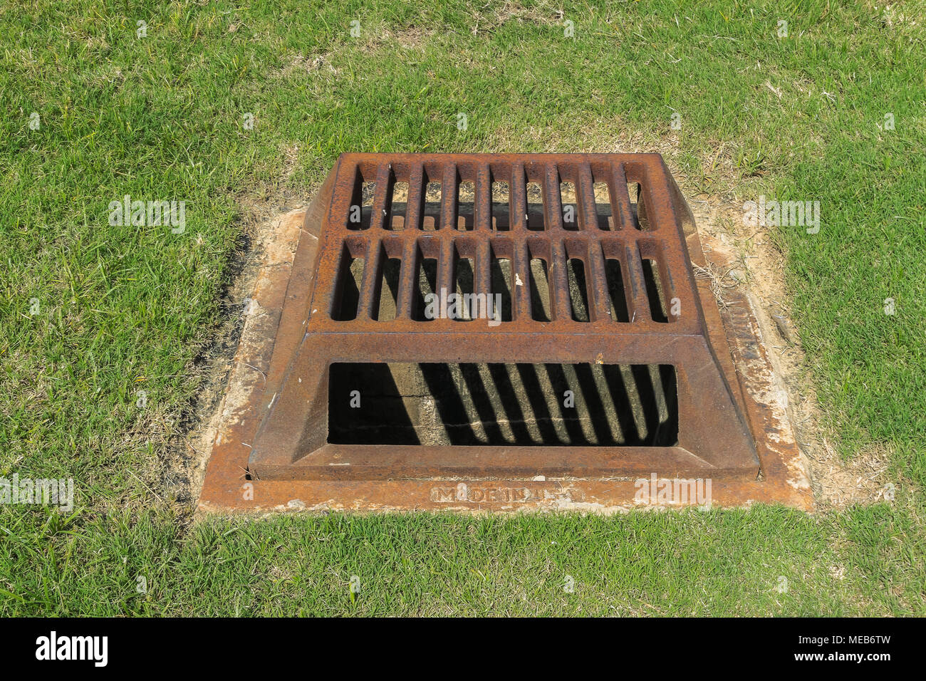 An old rusty iron, outdoor, drain cover for control of flooding after heavy rains. Cast in the USA. Stock Photo