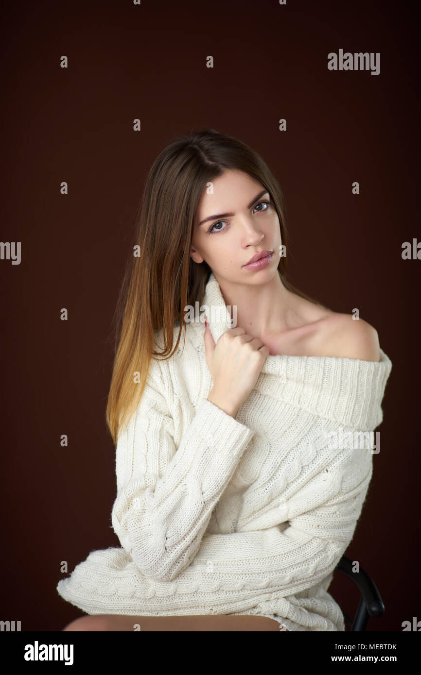 Concept: professional fashion lifestyle. Beautiful model posing in studio during classic test shooting wearing white sweater and white lingerie. Woman Stock Photo