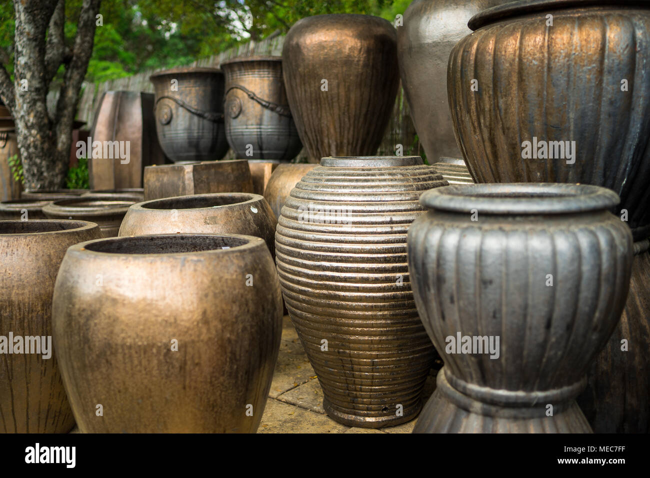 Large metallic brown coloured ceramic flower pots stacked at a plant