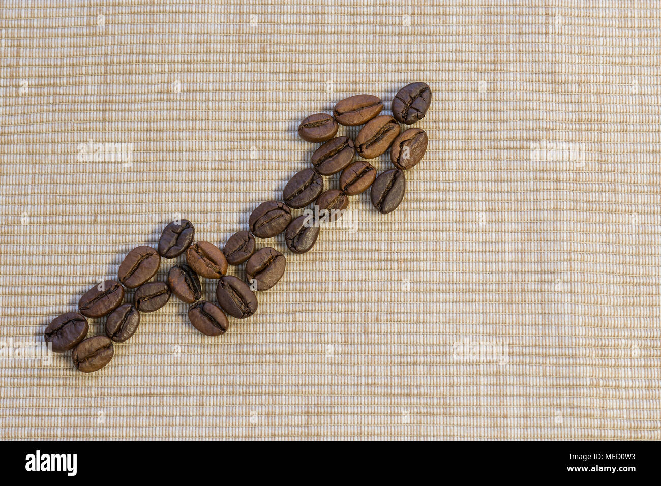 Coffee beans are laid out as a graph rising up on a beige napkin