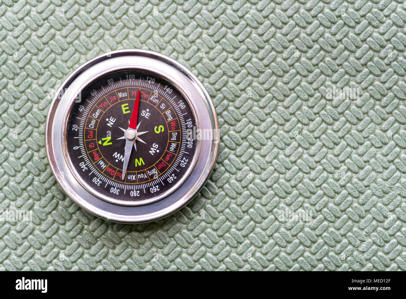 Compass lie on a green tourist rug. Equipment for traveling. Stock Photo