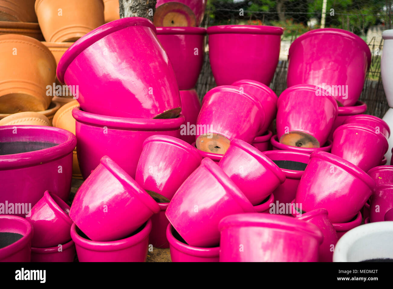 Large bright pink ceramic flower pots stacked at a plant nursery Stock