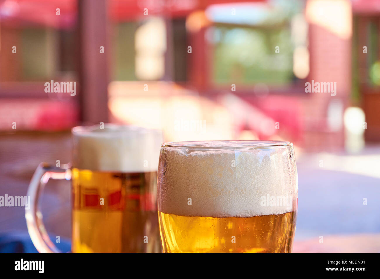 Two glasses of beer standing on a table in a garden pub on a summer sunny day with a blurred background Stock Photo