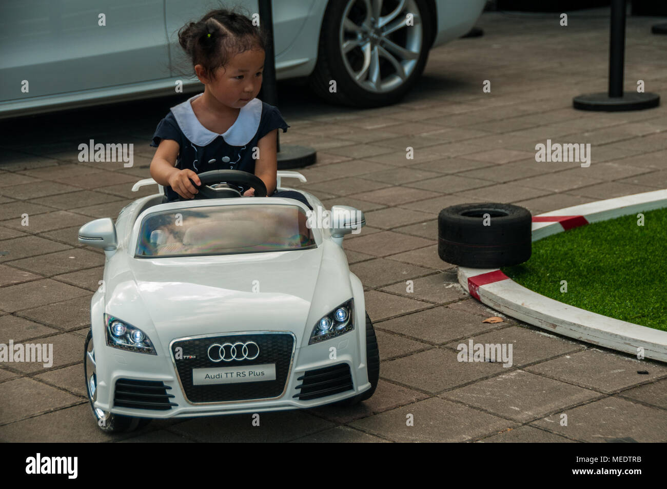 Young Chinese girl driving a miniature Audi TT RS Plus around an obstacle course at an Audi Sport event , part of a China GT race day, at the Shanghai Stock Photo
