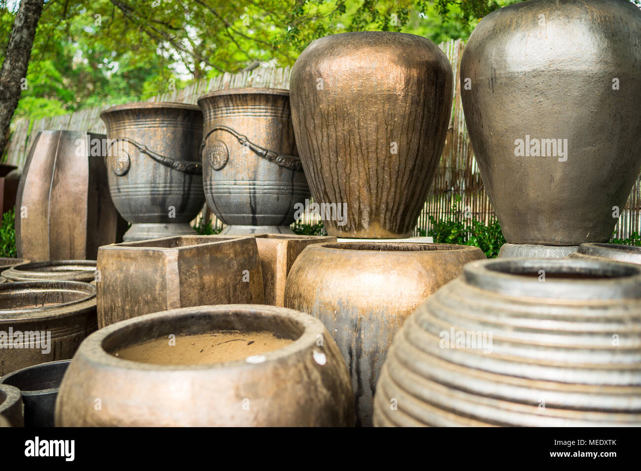 Large metallic brown coloured ceramic flower pots stacked at a plant