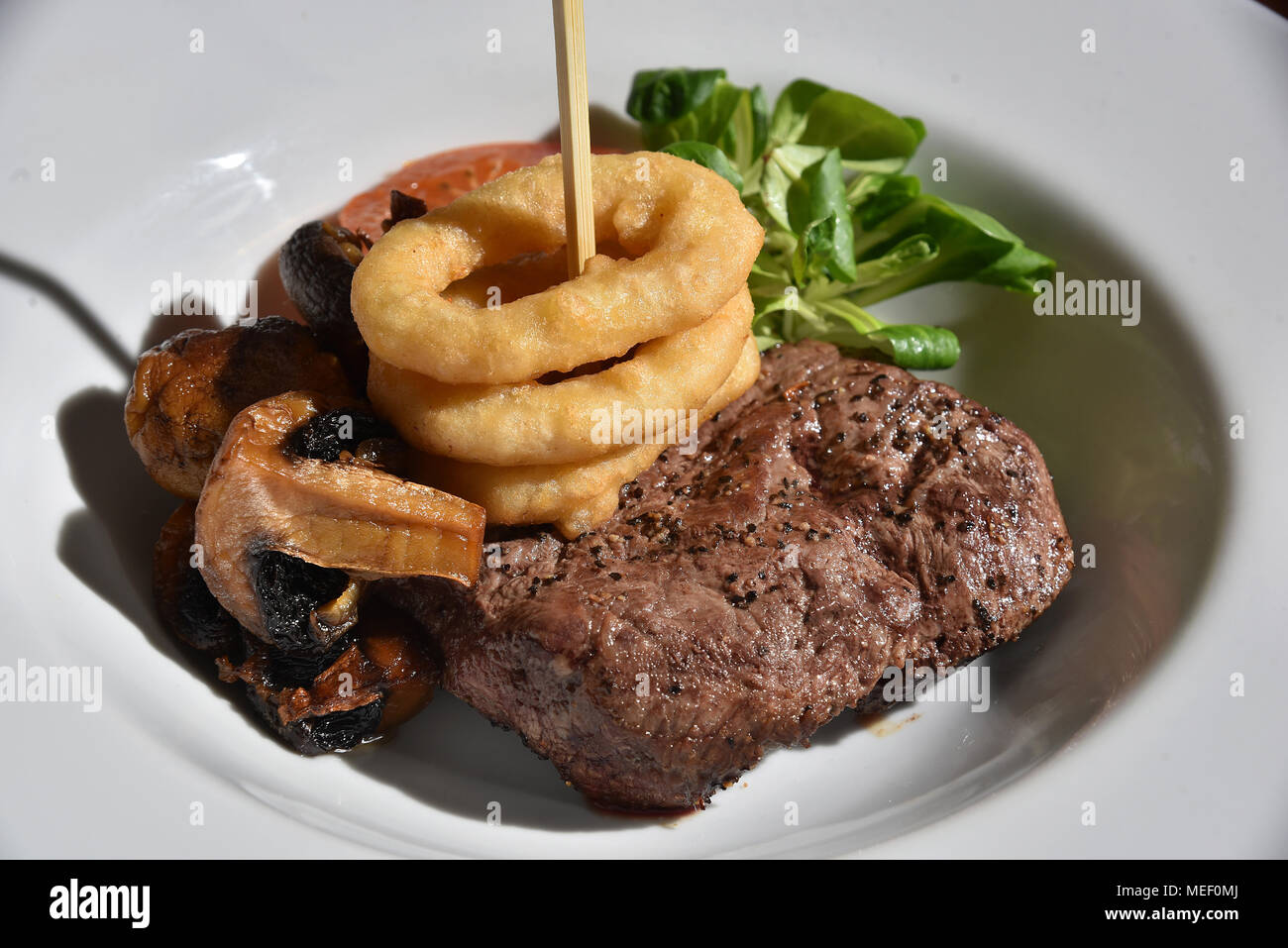 Pictures show plated food, cheese burger with onion rings tomato and lettuce, a steak and mushroom meal and a bacon and chicken dish. Stock Photo