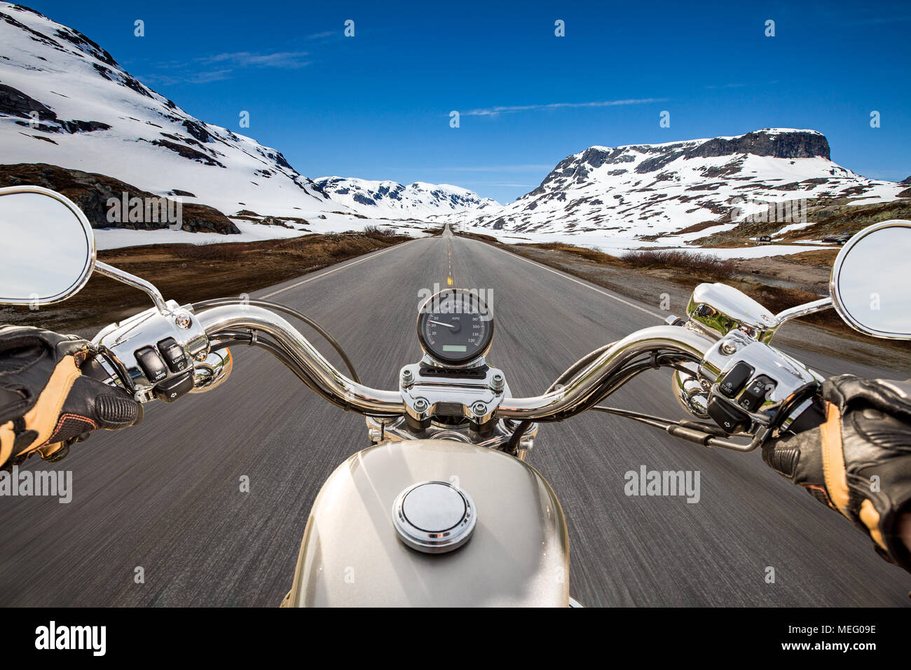 Biker driving a motorcycle rides along the asphalt road. First-person view. Stock Photo