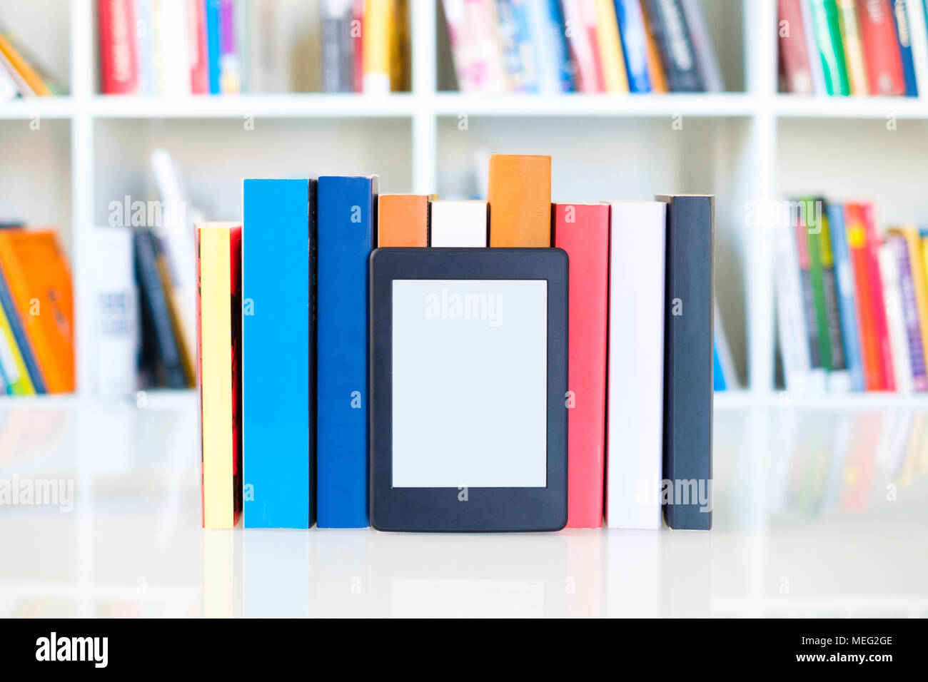 Ebook reader and paper books on bookshelf background.Copy space on