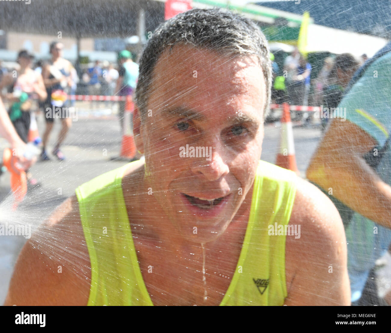 A runner uses a shower to cool off during the 2018 Virgin Money London Marathon. Stock Photo