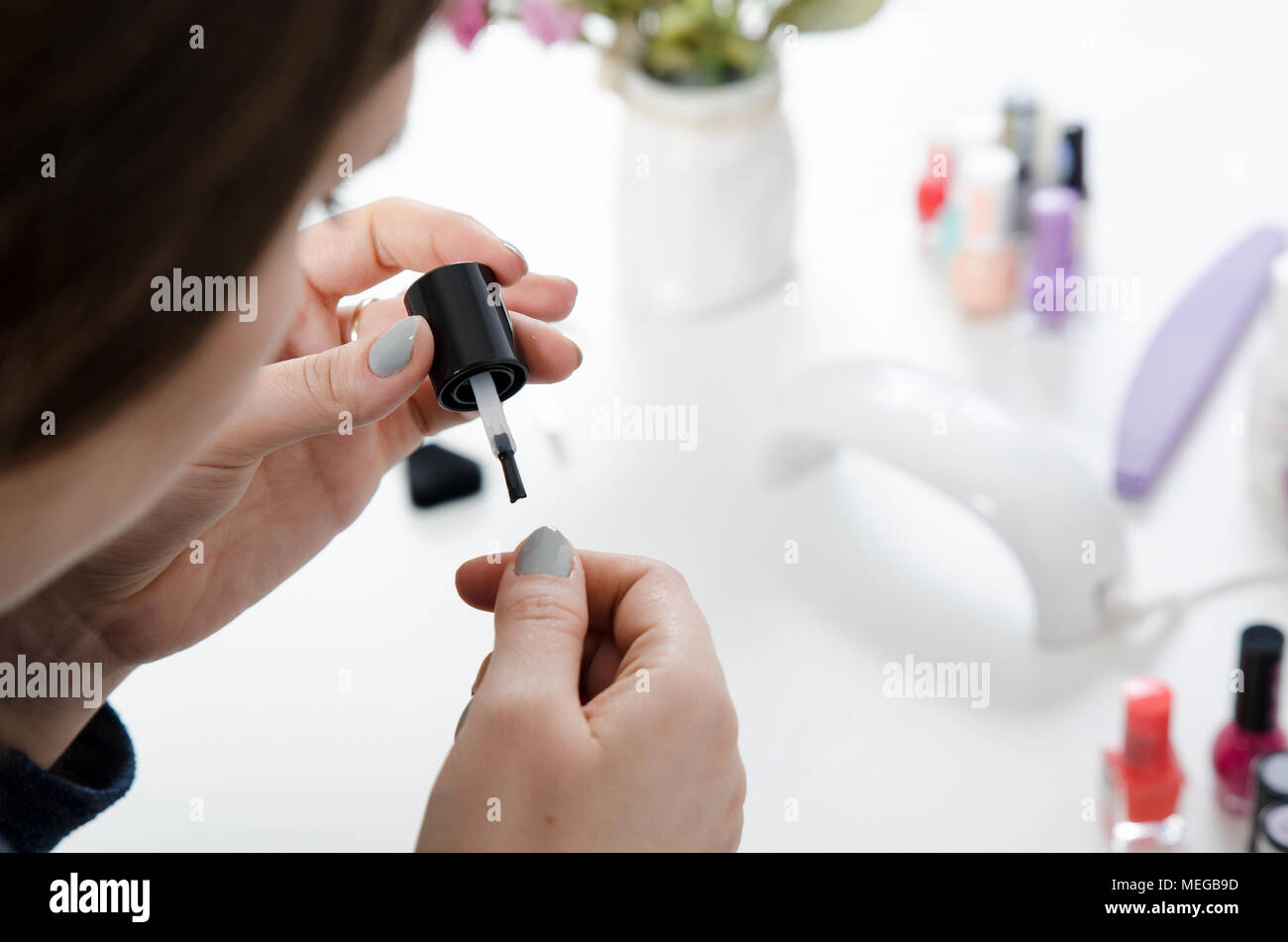 Woman carefully painting her finger nails. UV light dryer in background Stock Photo