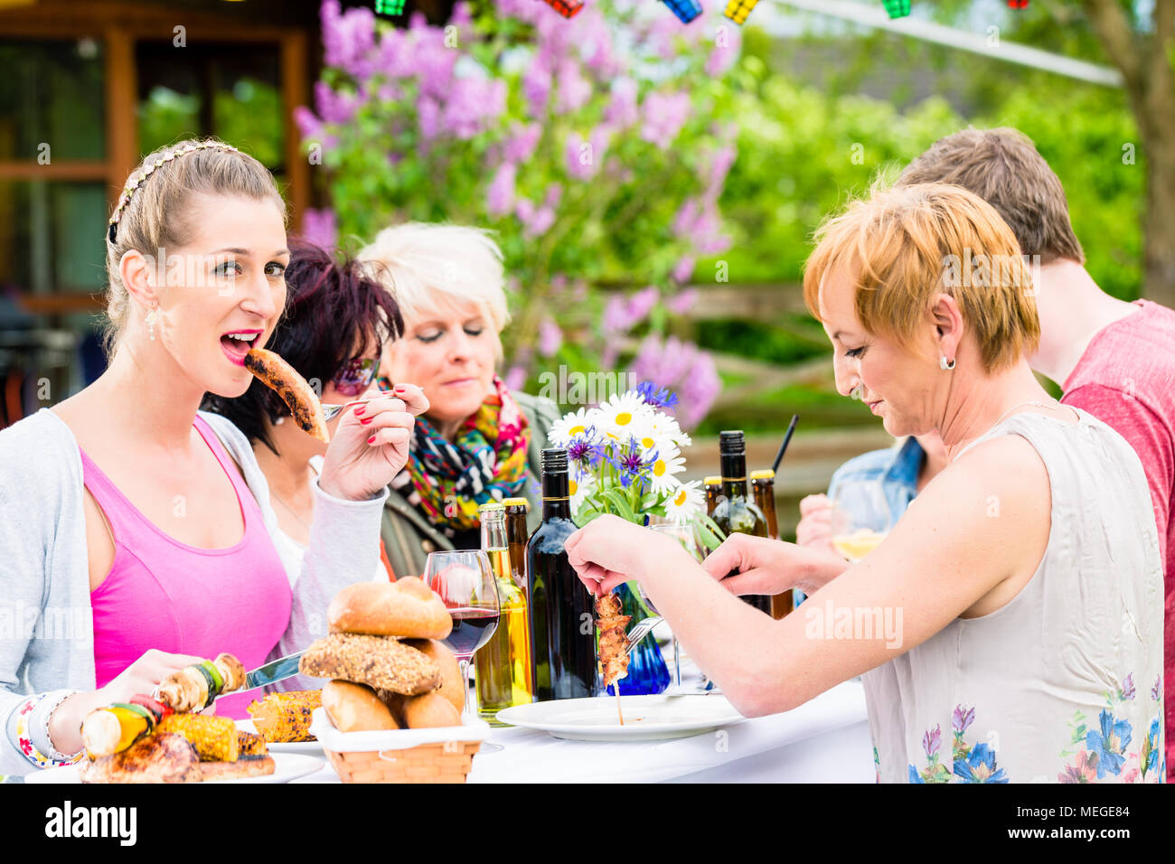 Woman eating grilled sausage on bbq party Stock Photo