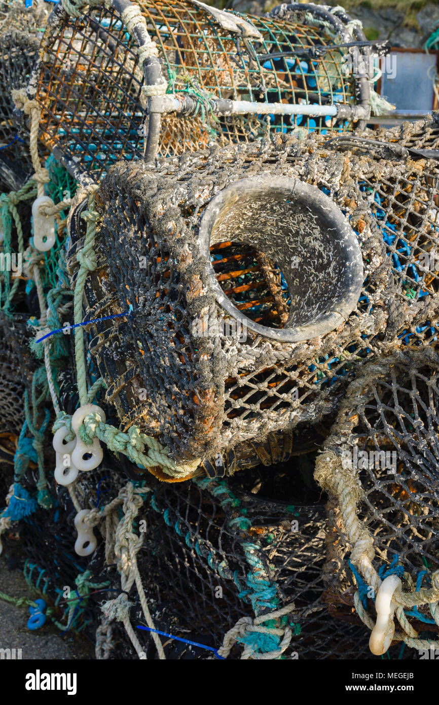 Lobster and crab pots or traps stacked on a harbour wall in Mevagissey Cornwall used for