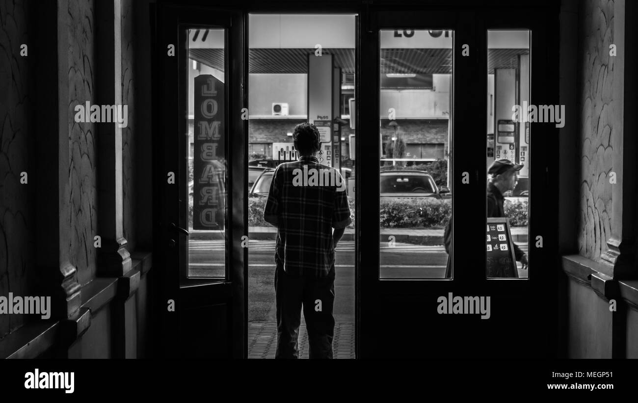 Young man standing at the antique glass doors in the tunnel and looks on the street in city center in Zabrze, Silesian Upland, Poland. Stock Photo