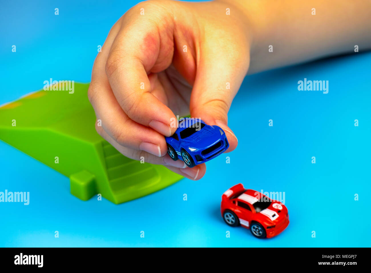 Tambov, Russian Federation - January 25, 2015 Child playing with Nano Speed Micro Cars on blue background. Studio shot. Stock Photo