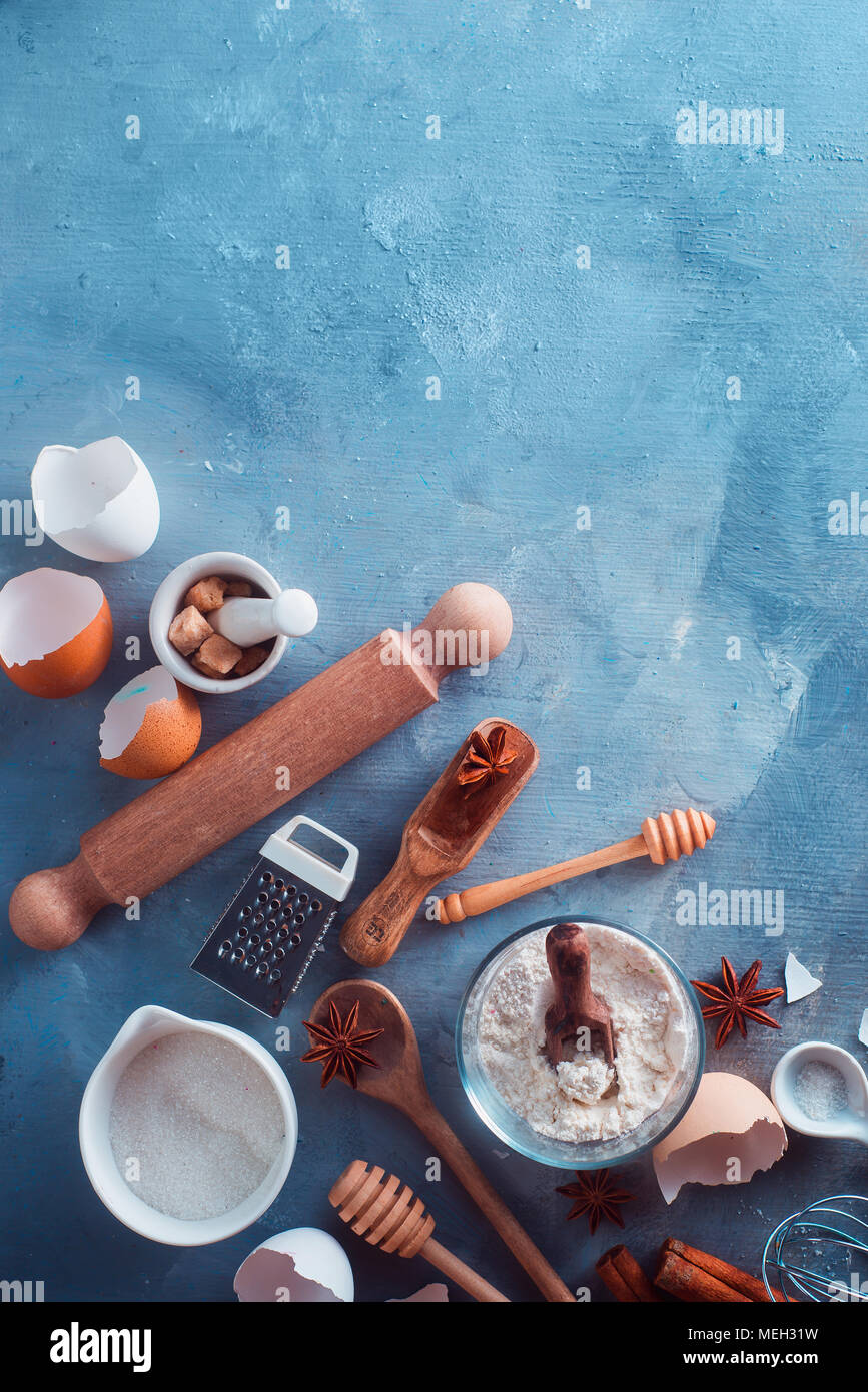Flat lay pastry preparation concept. Baking ingredients flat lay with flour, sugar, cinnamon, anise, eggs, rolling pin, grinder, honey spoons and measuring spoons. Concrete background with copy space Stock Photo
