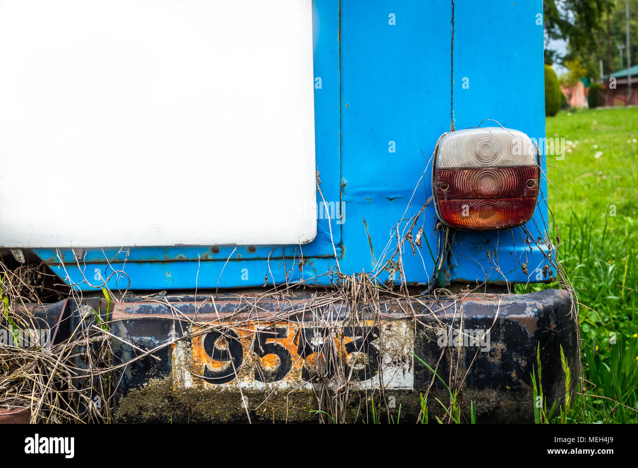 An abandoned vintage car white board tail-lamp lush green grass white billboard Stock Photo