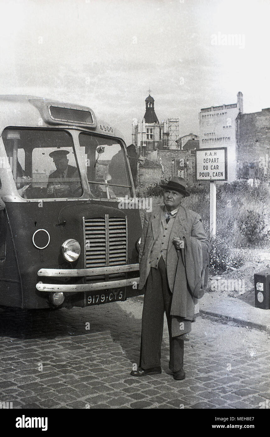 1950s, historical picture, a well-dressed elderly gentleman traveller with hat and coat waiting at Le Havre to board a bus to Caen, Normandy, France. Stock Photo