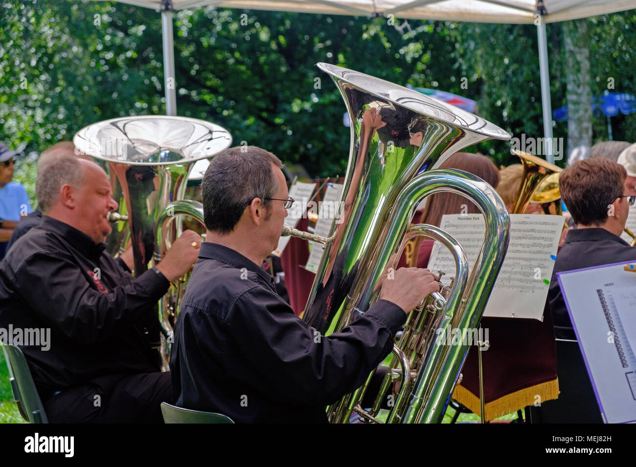 Two men play tubas in a band performing outside at Canons Park, Harrow