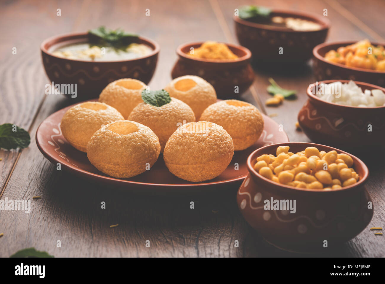 Pani Puri is Indian chat item served in a terracotta bowls and plate