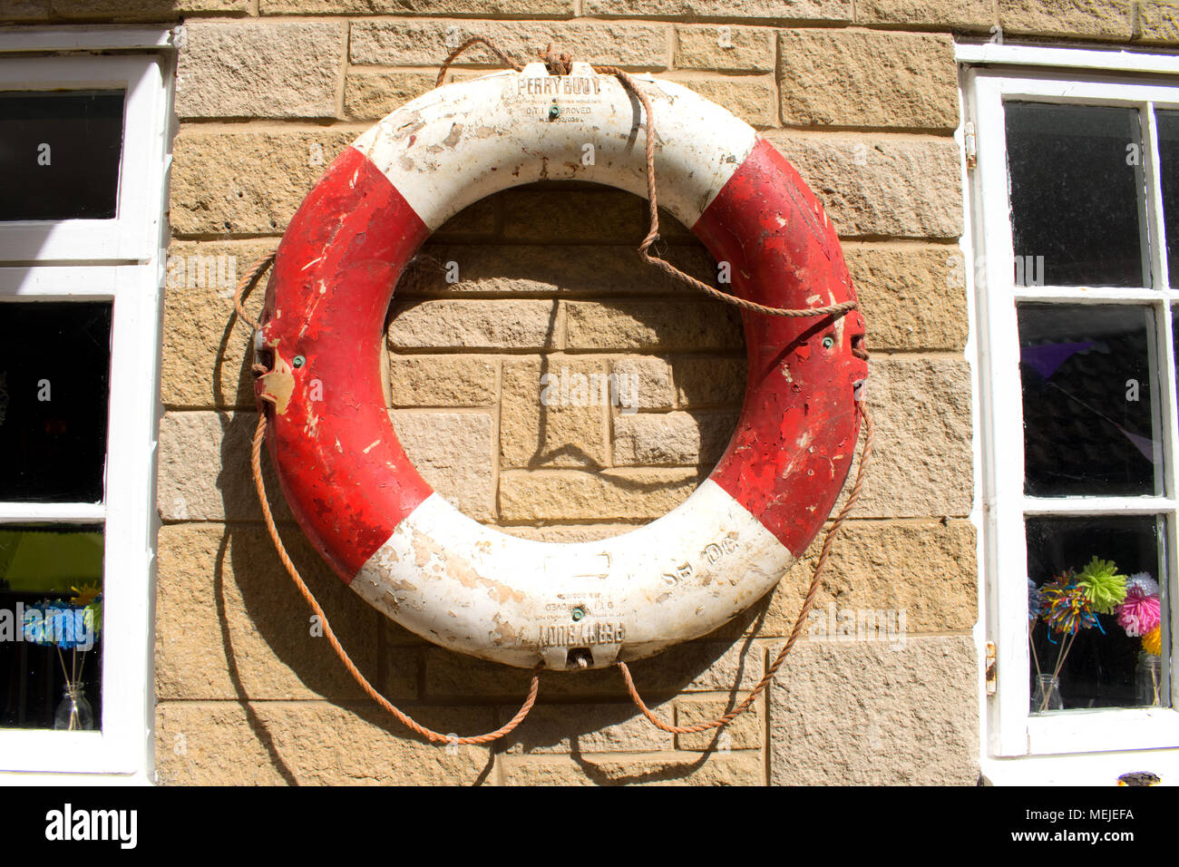 Life Buoy on a building.  Stone wall with red and white emergency ring Stock Photo