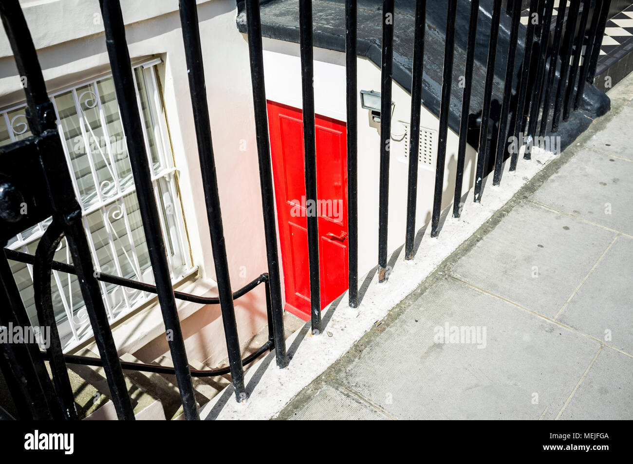 Red door at entrance of lower ground floor apartment in London. Stock Photo