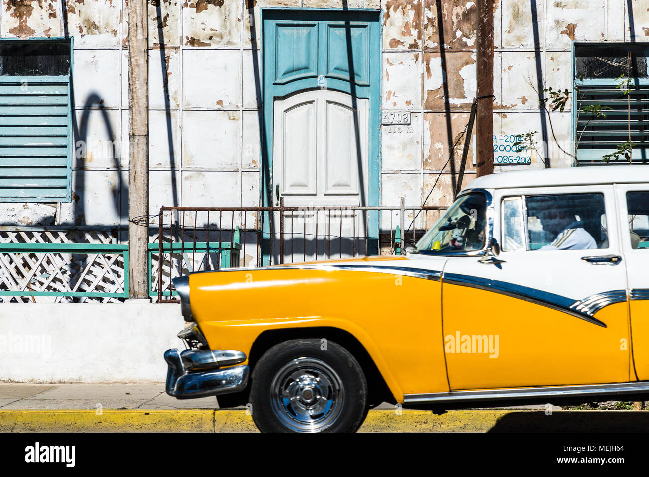 An old classic American car being driven outside a traditional building in Varadero, Cuba. Stock Photo
