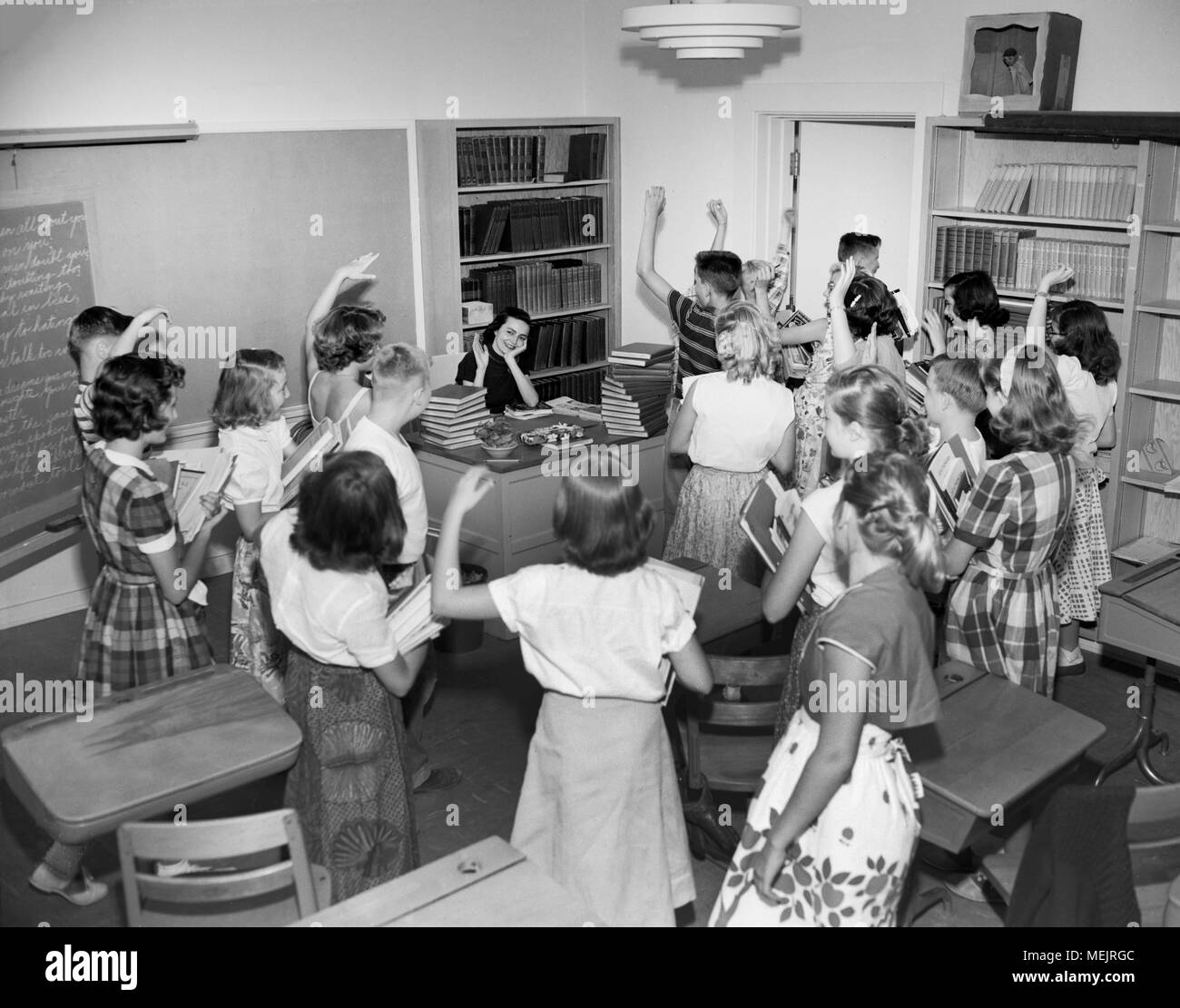 School children say goodbye to their teacher for the summer on the last day of school, ca. 1964. Stock Photo