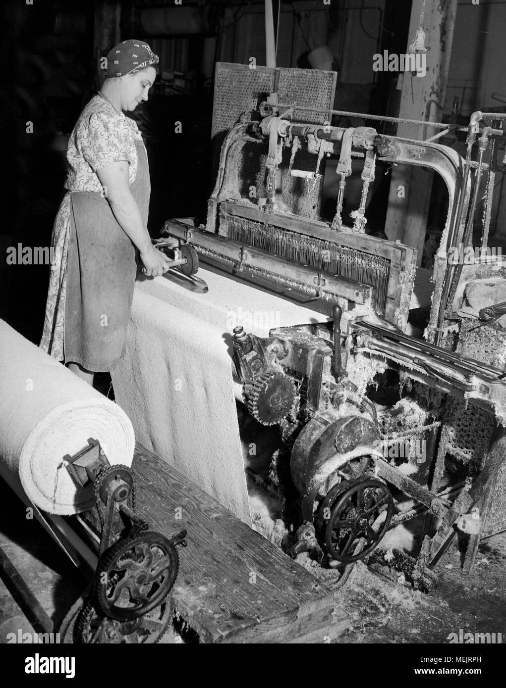 A worker watches an early industrial plastic manufacturing process in a